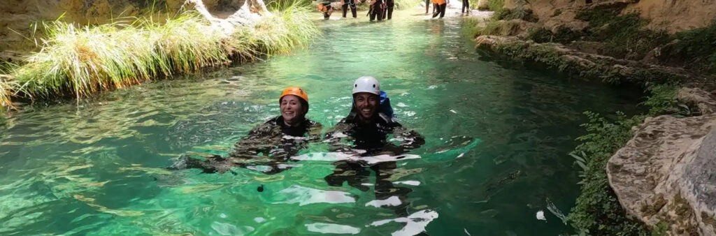 rio en el que se ven dos personas felices con casco en el agua